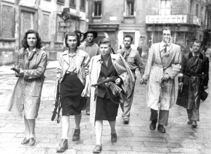 01-00074537000018 - 25 APRILE 1945 LA LIBERAZIONE - MILANO - TRE RAGAZZE TRA CUI LU' LEONE AGGREGATE AI GRUPPI PARTIGIANI , IN PIAZZA BRERA MENTRE PERLUSTRANO LA CITTA' INSIEME AI "GAPPISTI" - 26 APRILE 1945 .